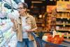Woman standing in a grocery store aisle, comparing product labels and making informed decisions about healthy food items for her family