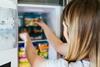Woman,Placing,Container,With,Frozen,Mixed,Vegetables,In,Freezer.
