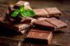 Chocolate,Pieces,With,Mint,On,Wooden,Table,Background
