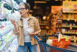Woman standing in a grocery store aisle, comparing product labels and making informed decisions about healthy food items for her family