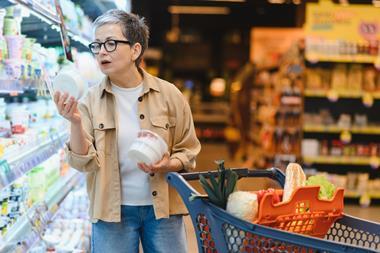Woman standing in a grocery store aisle, comparing product labels and making informed decisions about healthy food items for her family