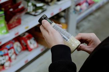 Shopper,Carefully,Examines,A,Sauce,Label,In,A,Grocery,Store