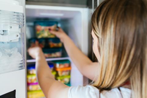 Woman,Placing,Container,With,Frozen,Mixed,Vegetables,In,Freezer.