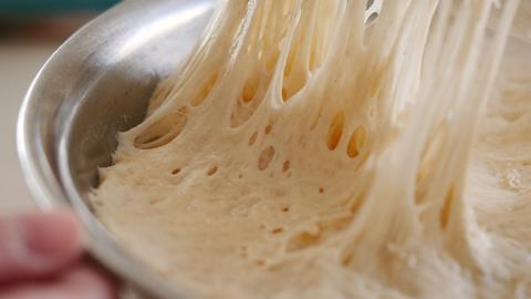 Pulling,Plastic,Wrap,Off,Risen,Bread,Dough,In,A,Metal