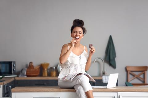 Young,African-american,Woman,Eating,Chocolate,In,Kitchen