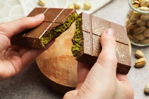 Woman,Breaking,Dubai,Chocolate,Bar,With,Pistachio,And,Knafeh,At
